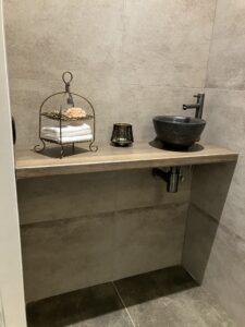 Toilet met houten plank en zwarte natuurstenen waskom