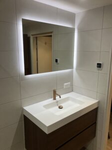 Wastafelmeubel met LED‑verlichte spiegel en koperen kraan