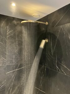 Douche met dubbele goudkleurige regendouche en zwarte marmerwand