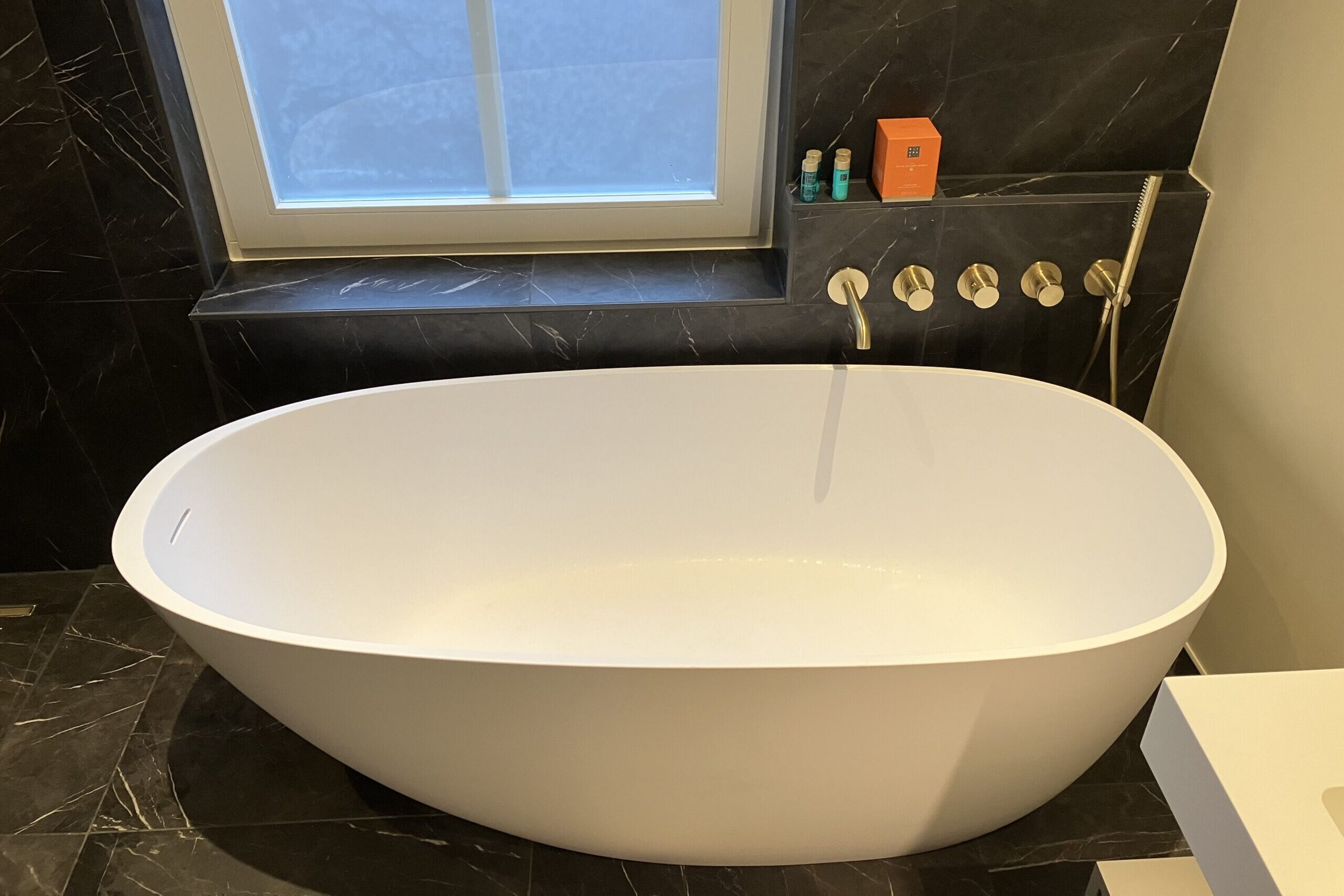 Luxe vrijstaand bad met gouden kranen in moderne badkamer