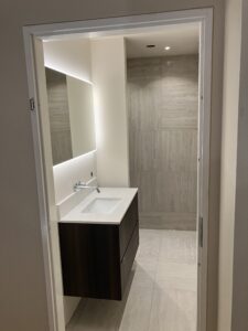 Kleine badkamer met LED‑spiegel, wastafel en inloopdouche